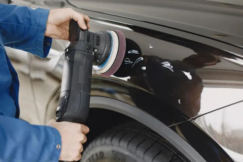 Dual-action polisher working compound into black paint during a paint correction