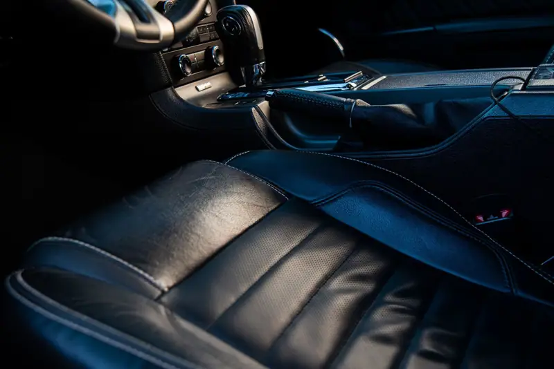 Clean black leather seat under cool blue cabin light after an interior detail