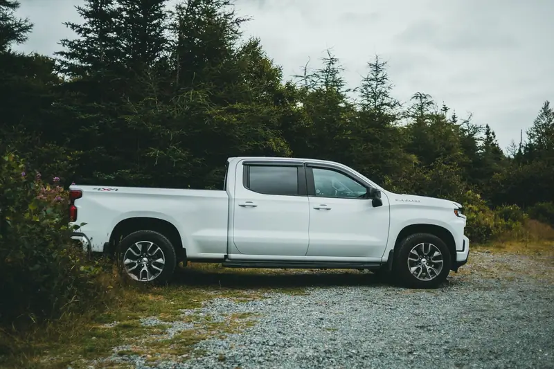White crew-cab work pickup parked on gravel