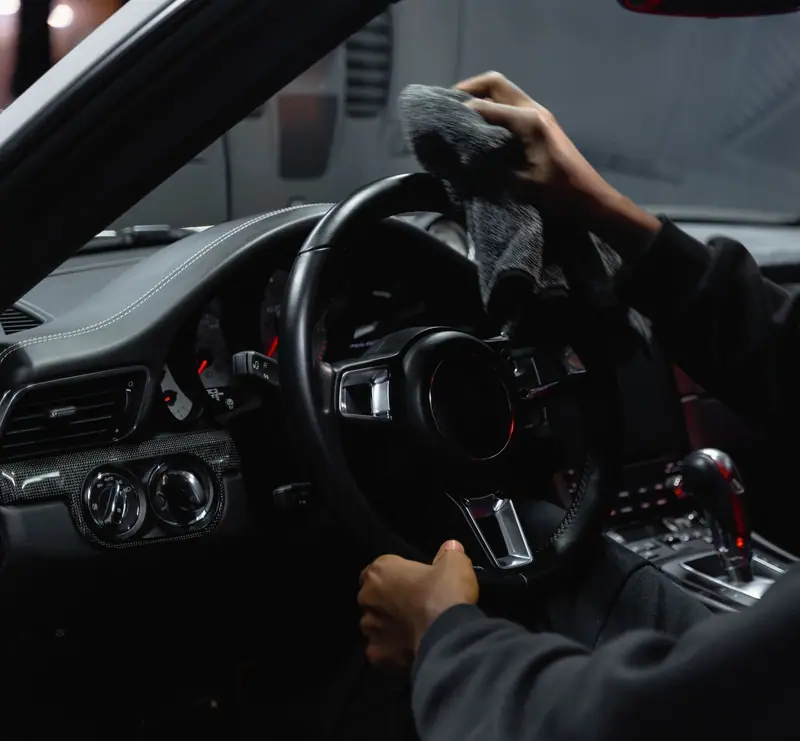 Microfiber towel wiping down a steering wheel during an interior detail