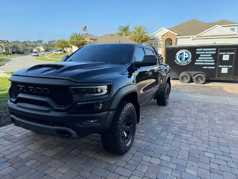 Coated Ram TRX in a Jacksonville-area driveway with the Maxx Perfection Detailing trailer behind it